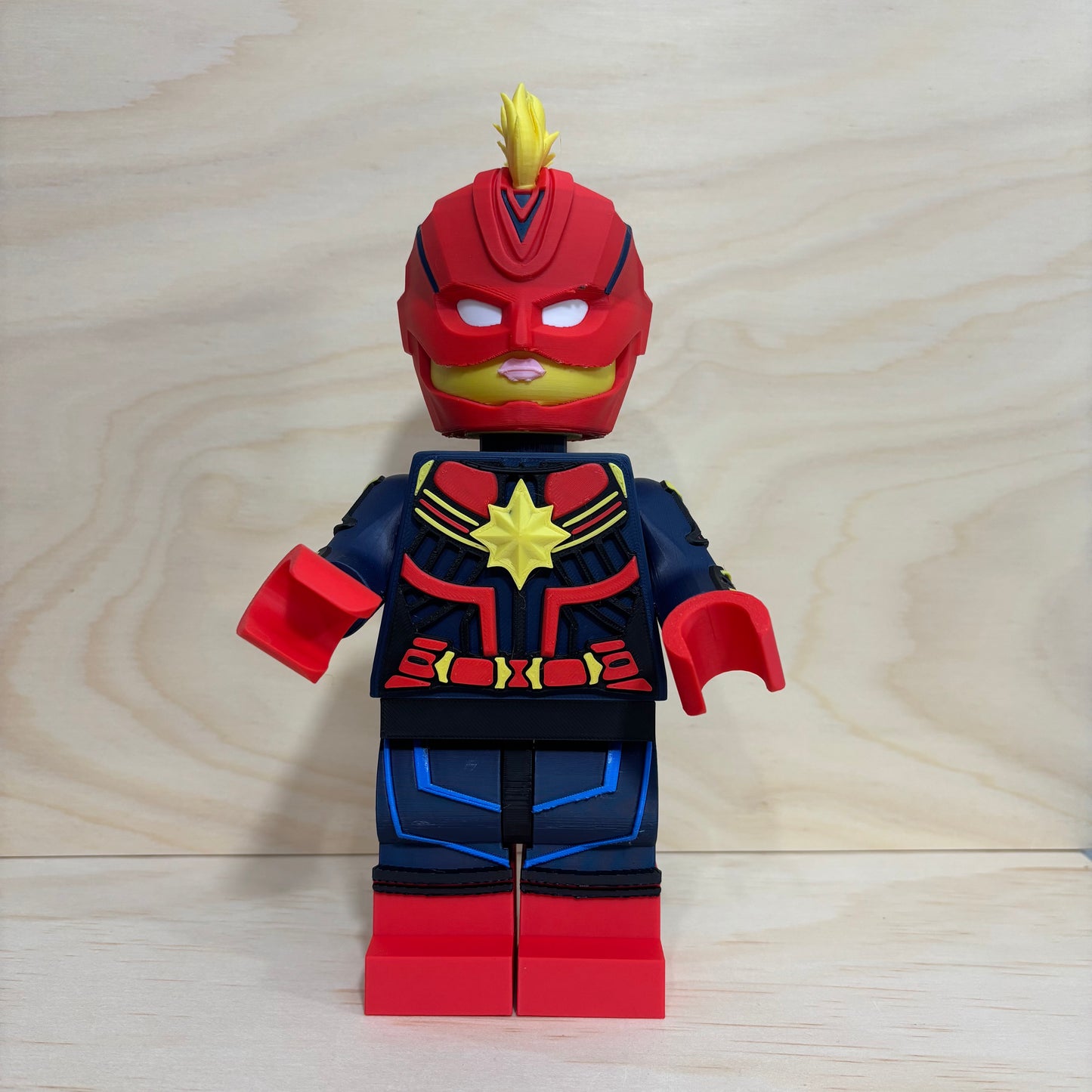 3D printed Captain Marvel Brickman Figure wearing the iconic red, blue and gold suit with mohawk helmet.