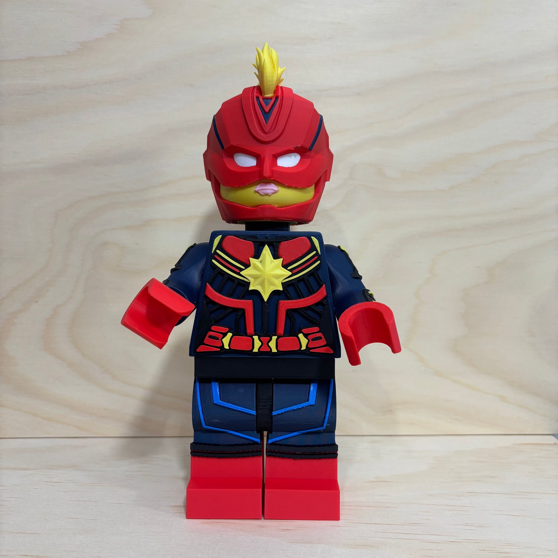 3D printed Captain Marvel Brickman Figure wearing the iconic red, blue and gold suit with mohawk helmet.