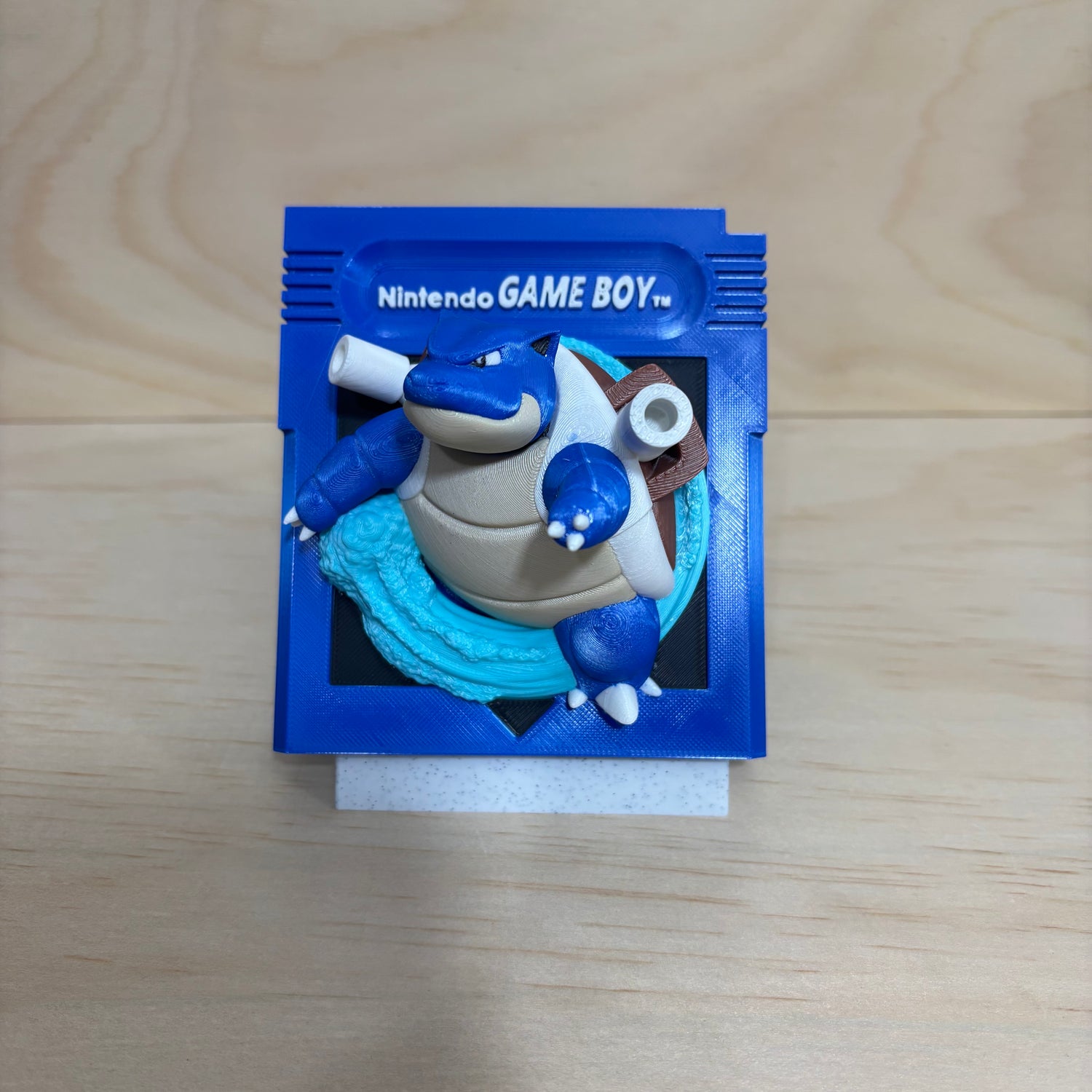3D printed 0009 Blastoise Game Boy cartridge-inspired display featuring Blastoise bursting through a retro handheld game cartridge with dynamic water effects.
